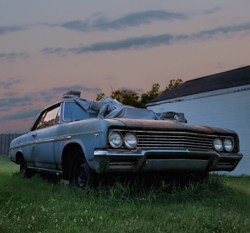 Junk blue chevrolet camaro convertible coupe parked on green grass field during daytime