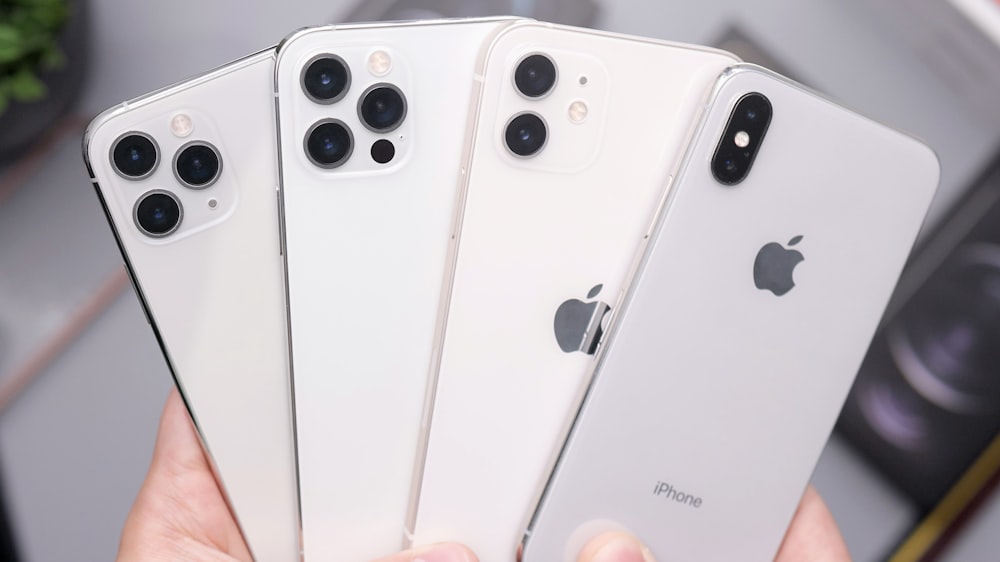 a person holding four iphones in their hands