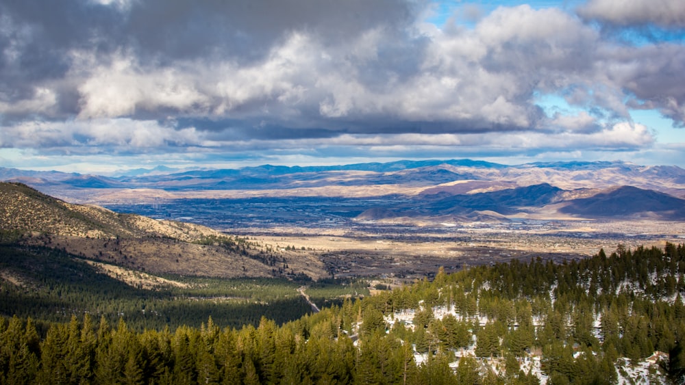 green trees and mountains under white clouds and blue sky during daytime