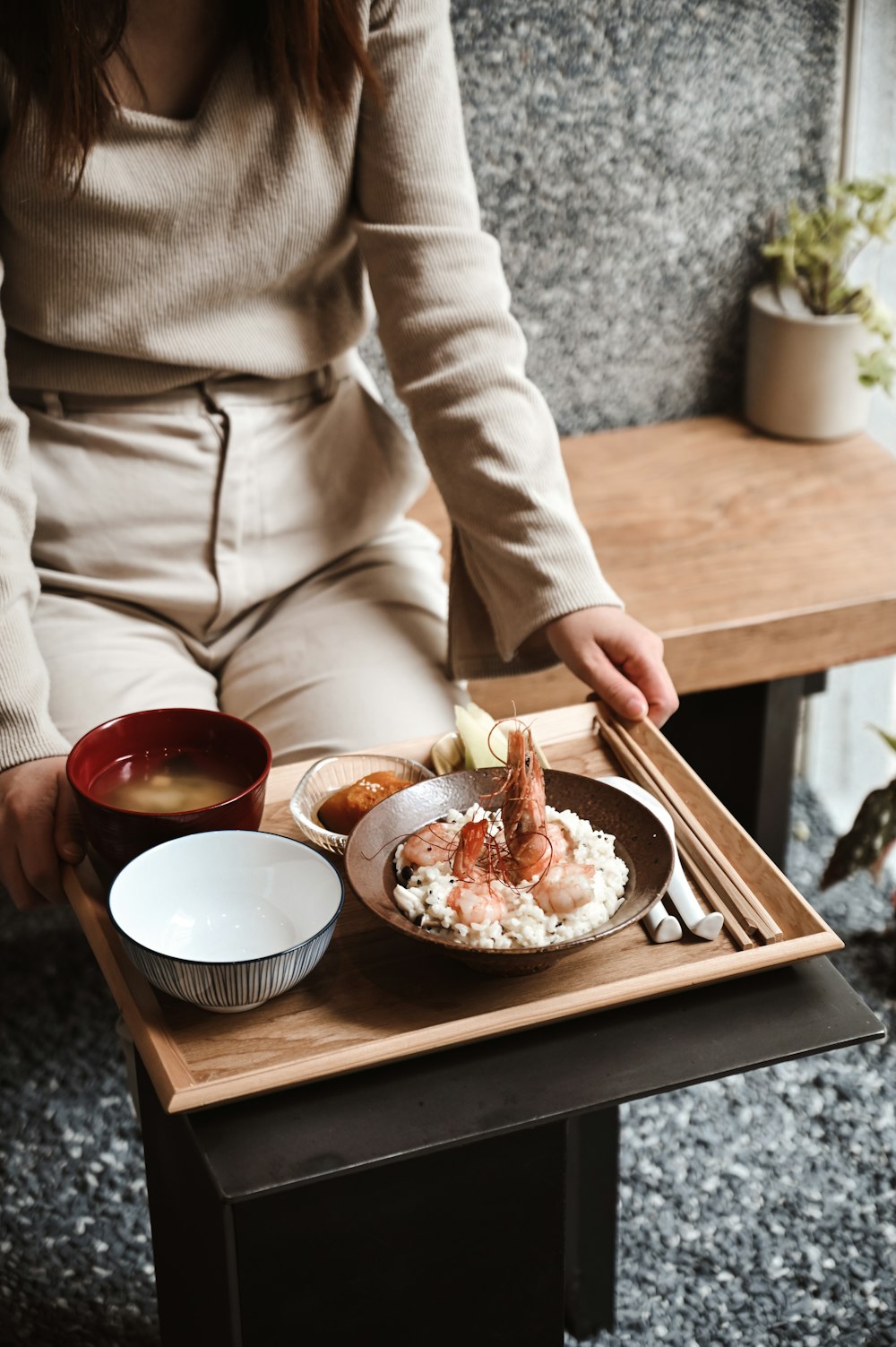 person in beige long sleeve shirt holding brown wooden tray with food