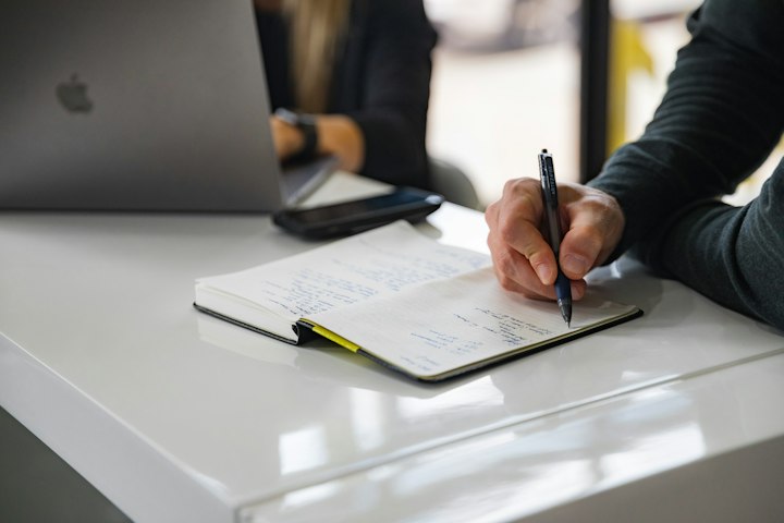 Conseiller prenant des notes manuscrites à côté de son ordinateur portable après un rendez-vous