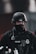 A police officer wearing tactical gear, including a black helmet and a face cover, is seen. The officer's uniform displays a police badge and has various equipment attached, including a radio and other tactical gear.