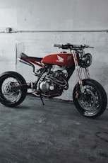 red and black motorcycle parked beside white wall