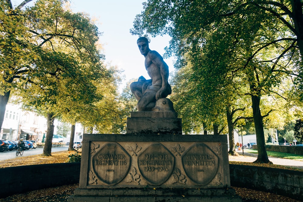 man statue near green trees during daytime