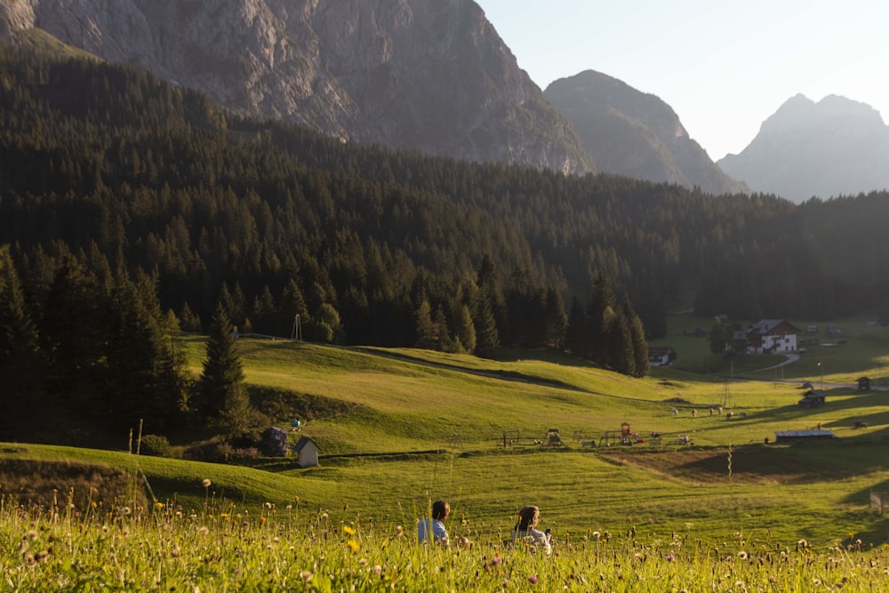 people walking on green grass field near green trees and mountain during daytime