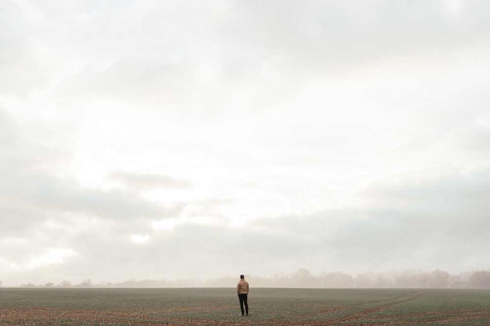 man in black shorts standing on brown field under white cloudy sky during daytime