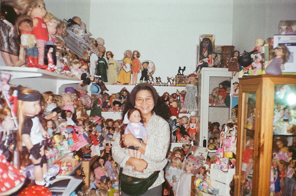 girl in white sweater standing beside plush toys