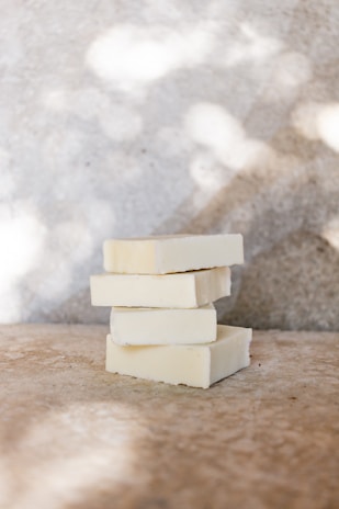 Stacked picksoap bars with unique designs, illuminated by soft natural light near a window.