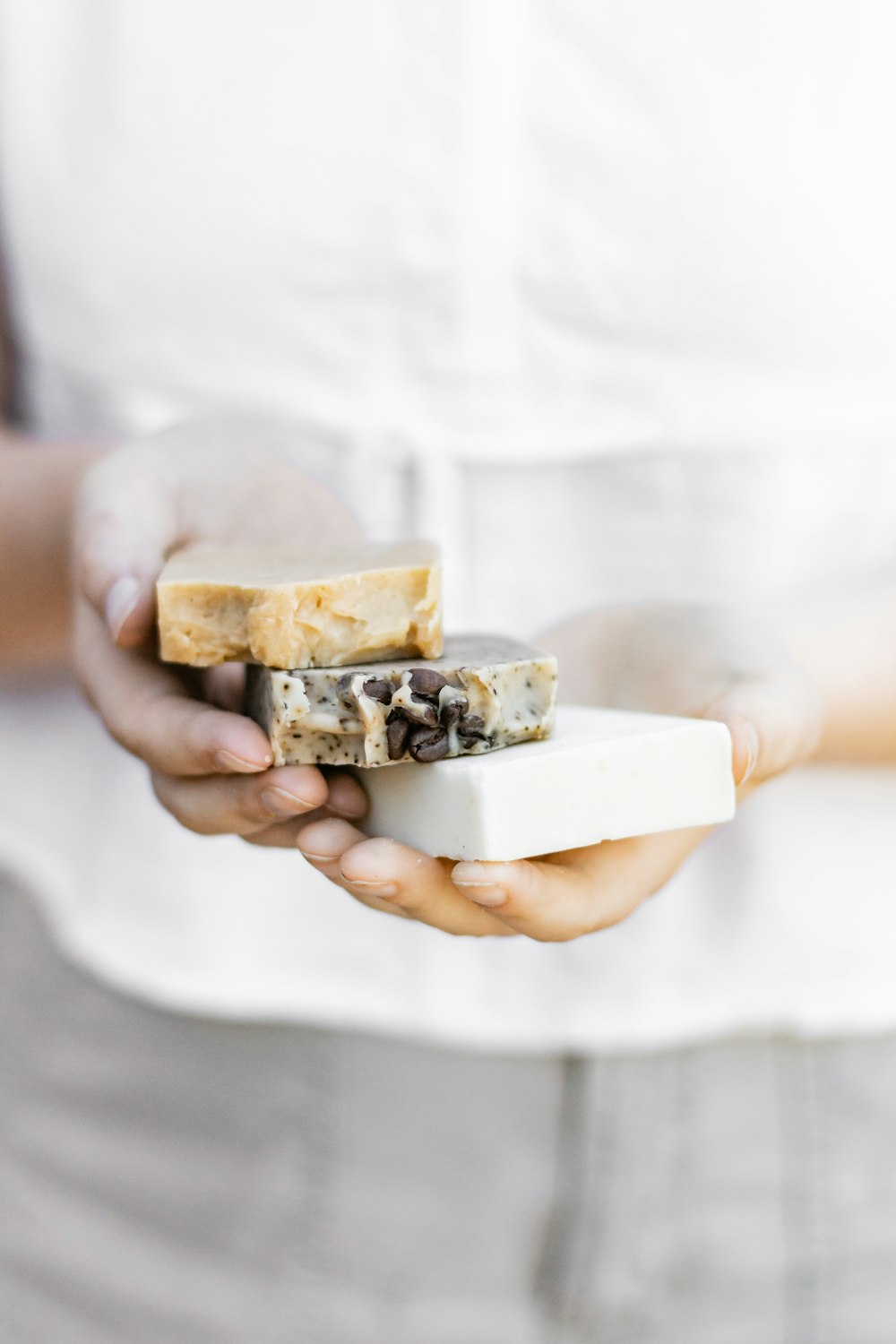 A square, close-up shot of a hand-cut bar of lavender soap showing natural botanical flecks and a rustic texture