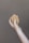 A hand holding a piece of brown soap against a plain background. The soap has a natural, handmade appearance with a slightly uneven surface.