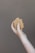 A hand holding a piece of brown soap against a plain background. The soap has a natural, handmade appearance with a slightly uneven surface.