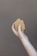 A hand holding a piece of brown soap against a plain background. The soap has a natural, handmade appearance with a slightly uneven surface.