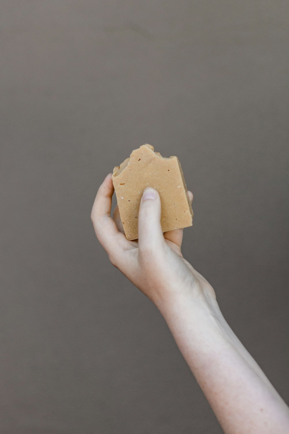 person holding brown wooden ornament