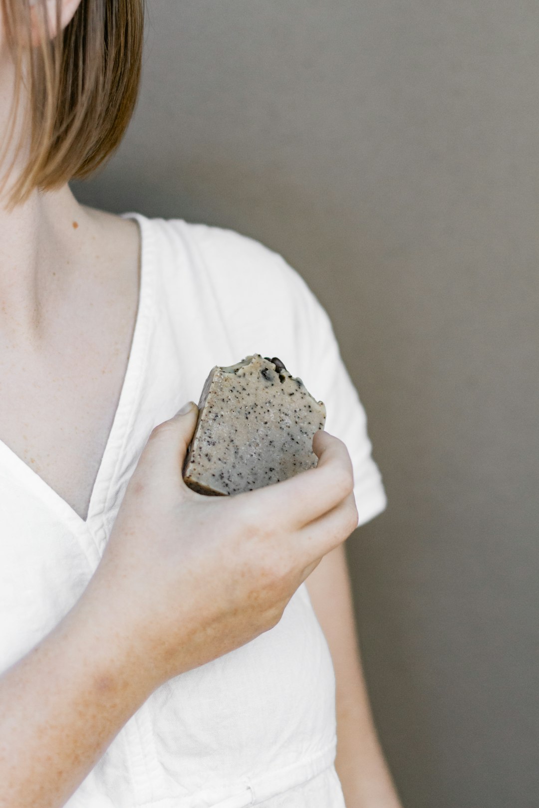 woman in white v neck shirt holding brown and black stone