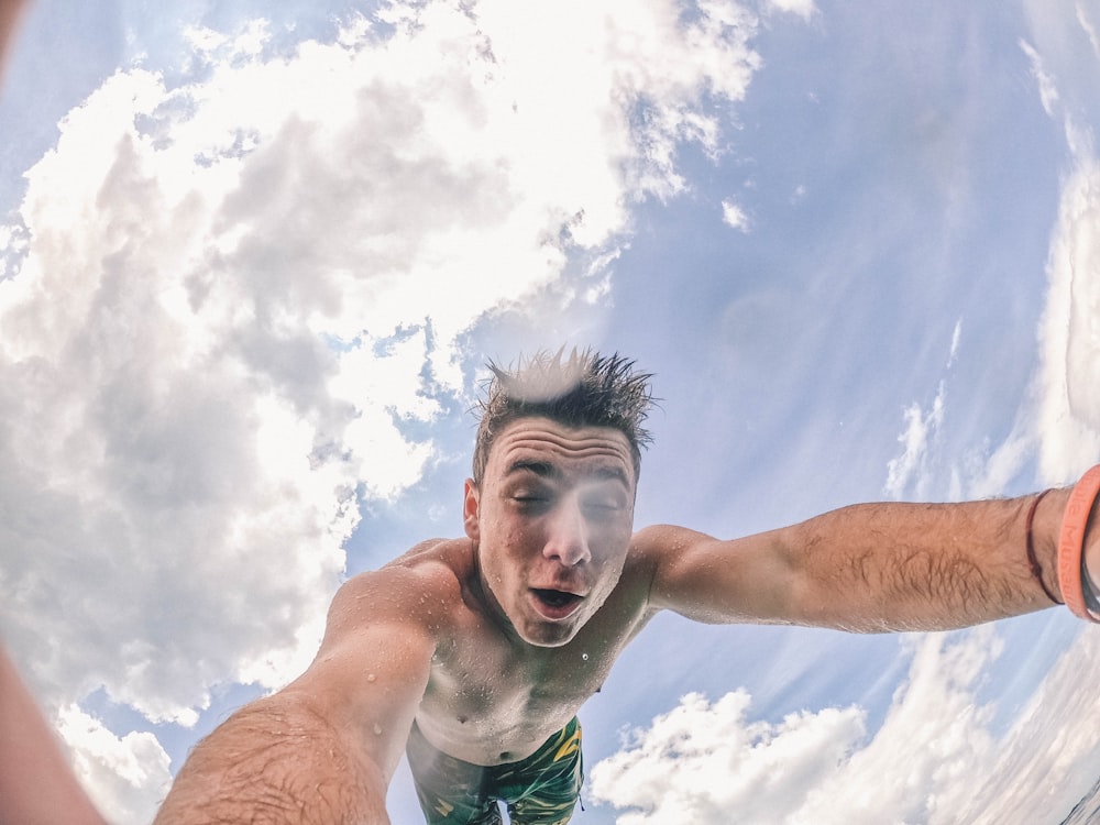 man in green shorts under white clouds and blue sky during daytime