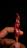 Close-up of a hand holding a vibrant, spicy dried fruit snack with chili flakes.