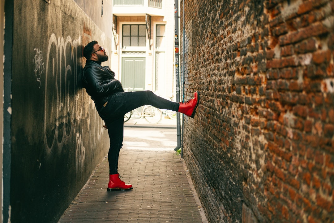 woman in black leather jacket and black pants walking on sidewalk during daytime