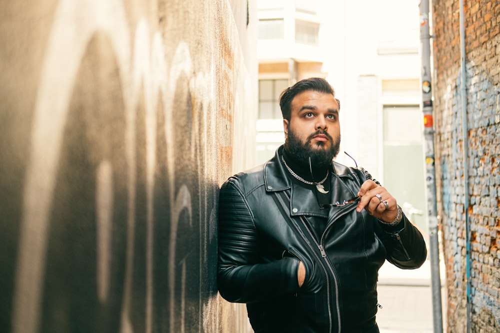 man in black leather jacket standing beside white curtain