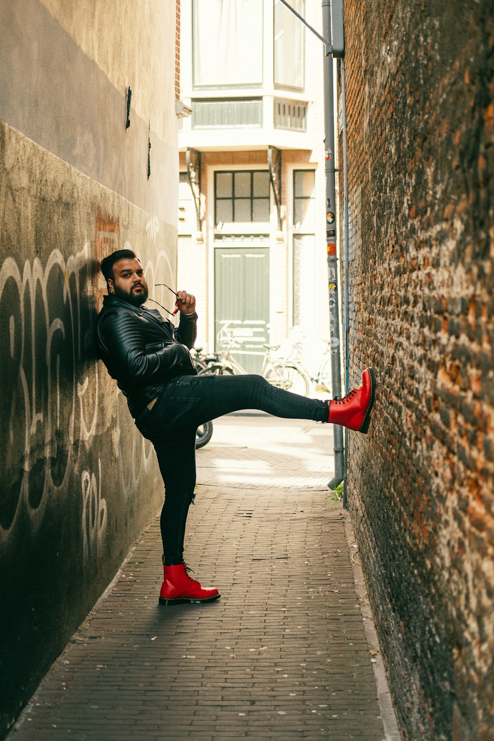 man in black leather jacket and black pants jumping on gray brick wall during daytime