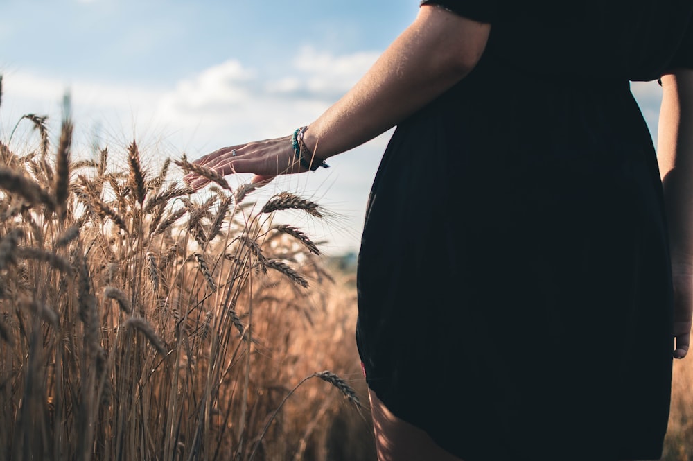 person in black t-shirt standing on brown grass field during daytime