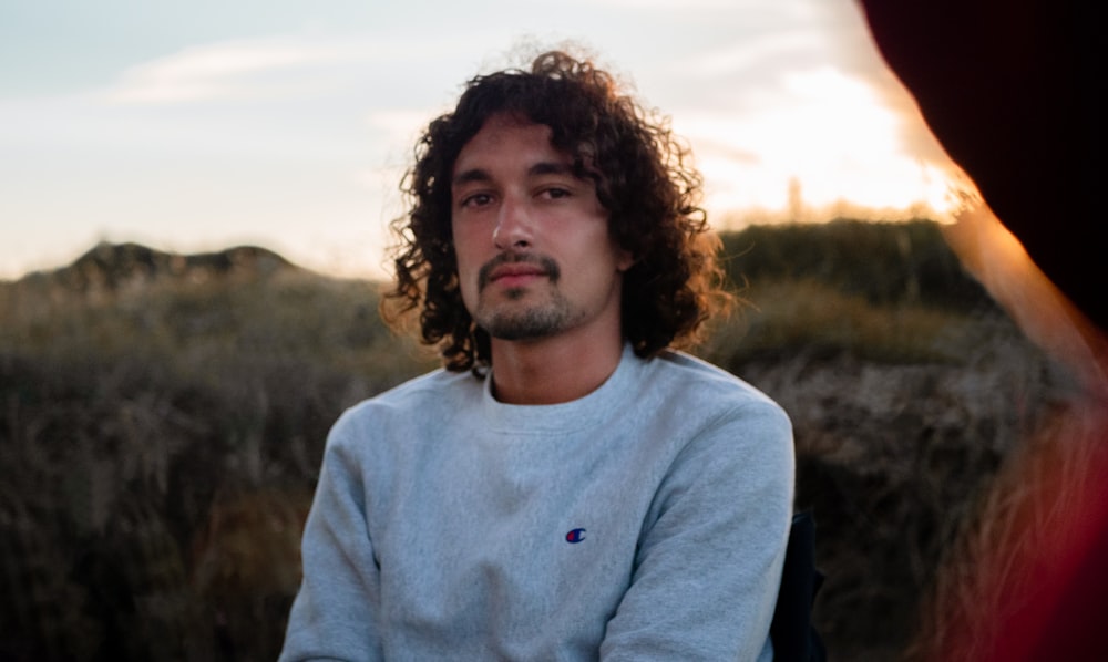 man in blue crew neck sweater standing on green grass field during daytime