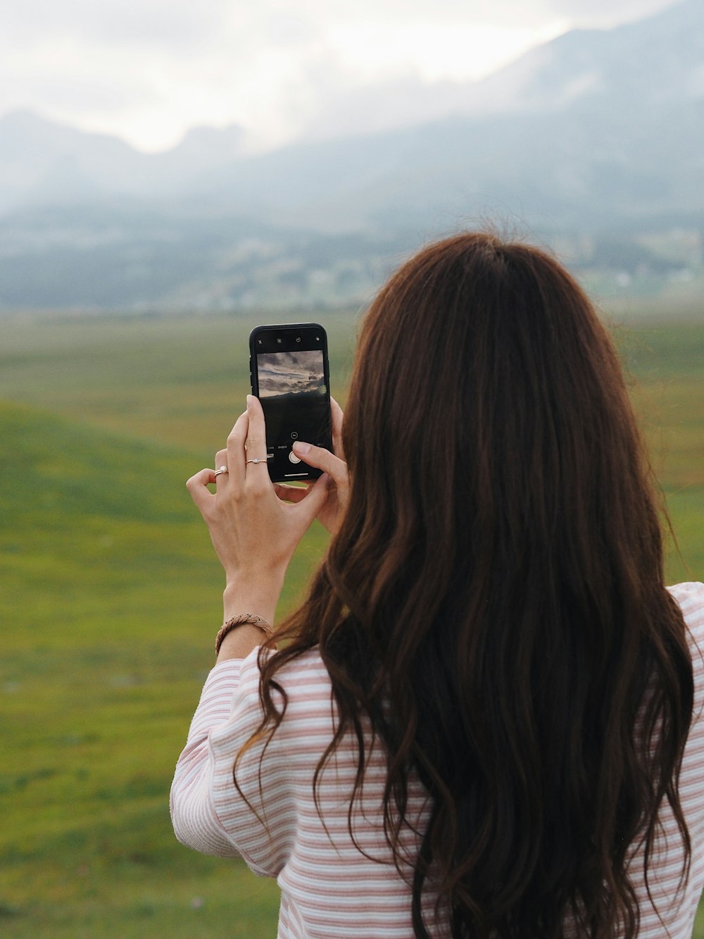 woman in white and black stripe shirt holding iphone