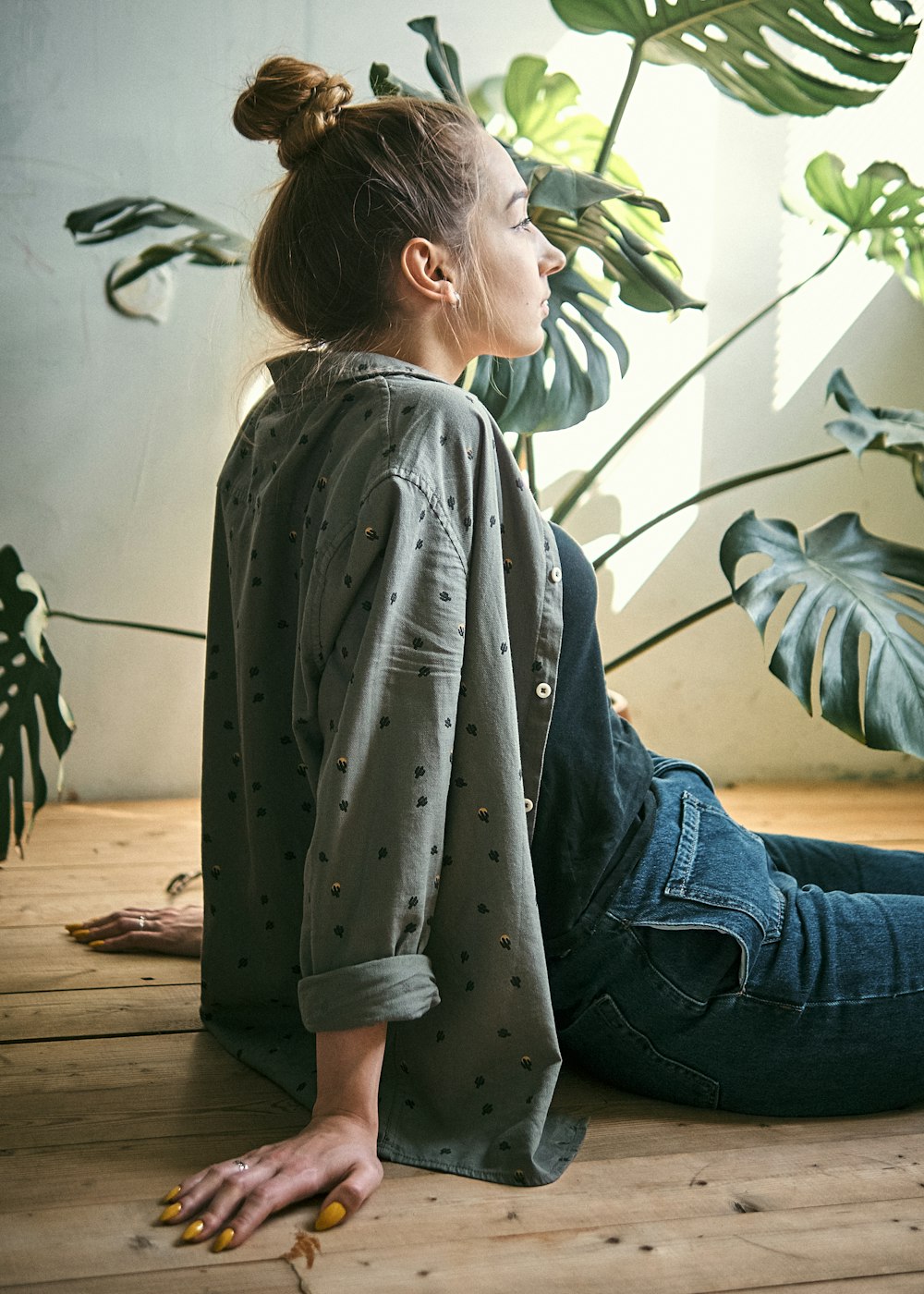 woman in gray shirt and blue denim jeans sitting on brown wooden floor