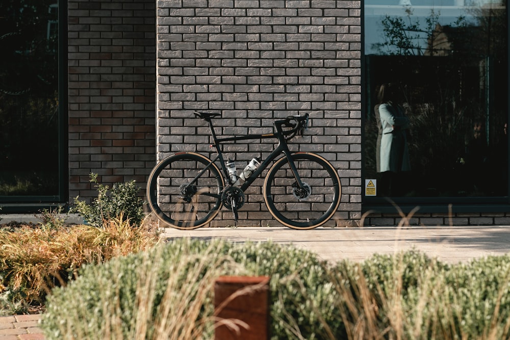 black and gray mountain bike beside brown brick wall