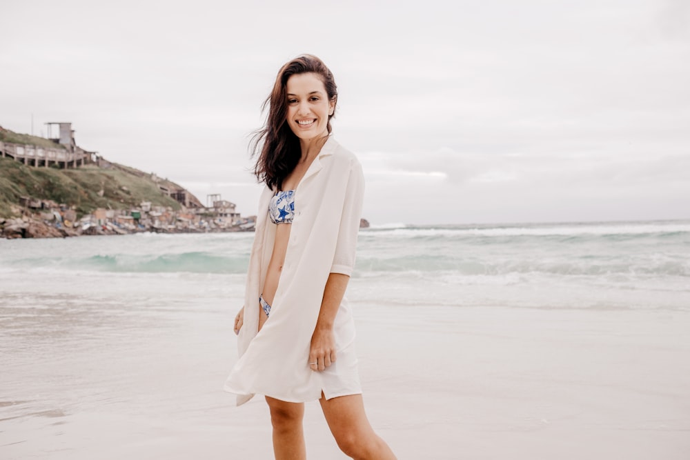 femme en robe blanche à manches longues debout sur la plage pendant la journée
