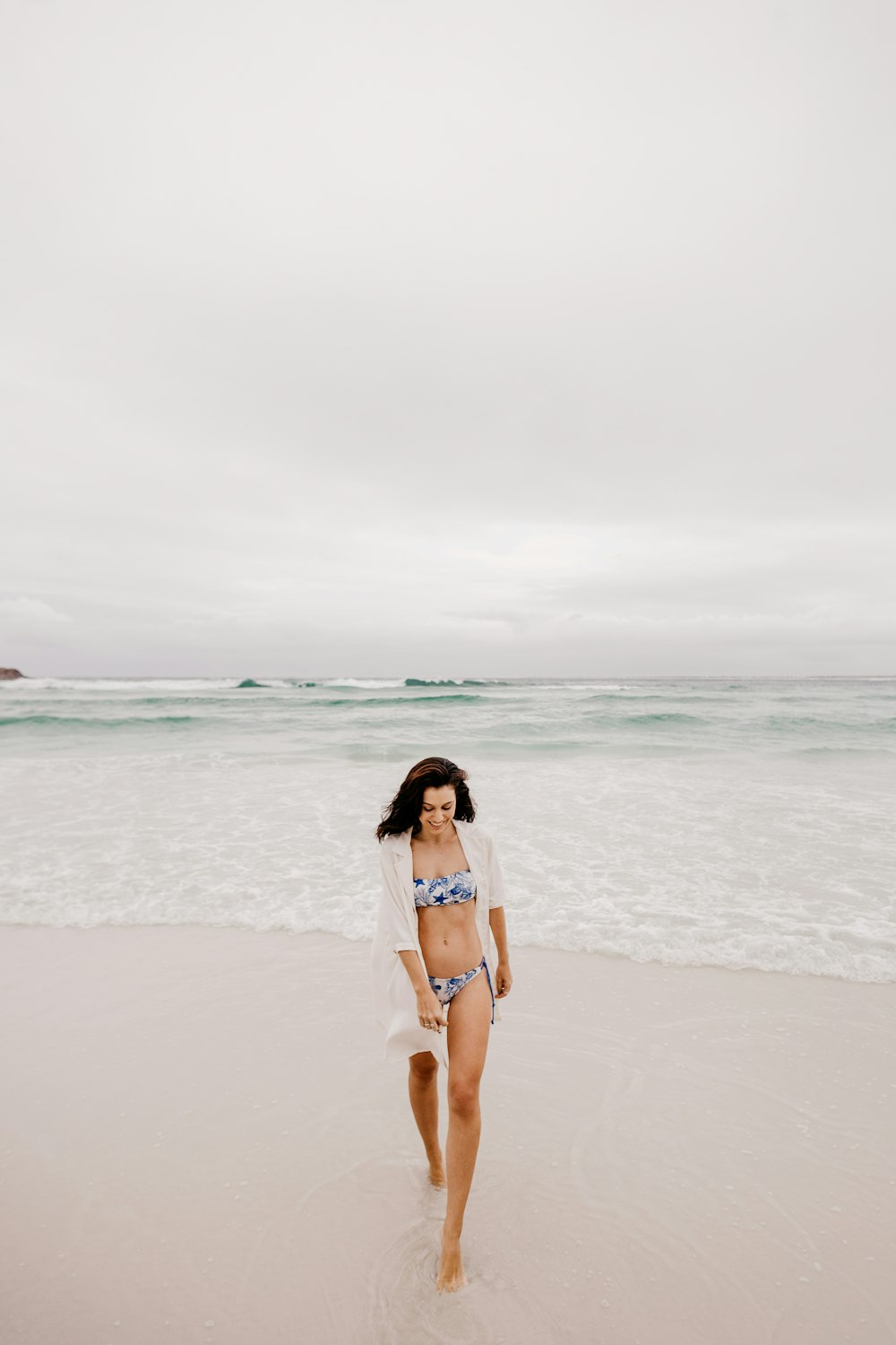 woman in white bikini standing on beach during daytime