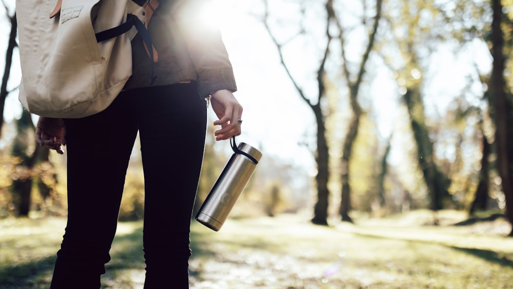 man in gray dress shirt and black pants holding stainless steel vacuum flask