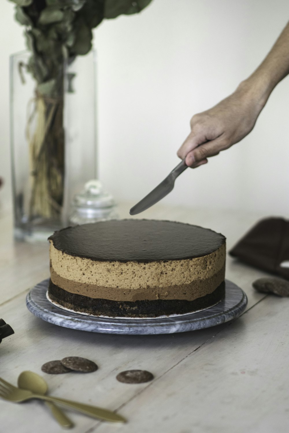 person slicing chocolate cake on black ceramic plate