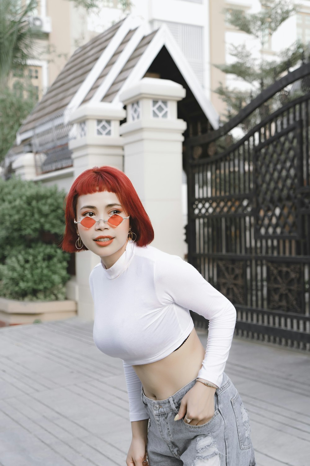 woman in white long sleeve shirt and white shorts standing on gray concrete floor during daytime