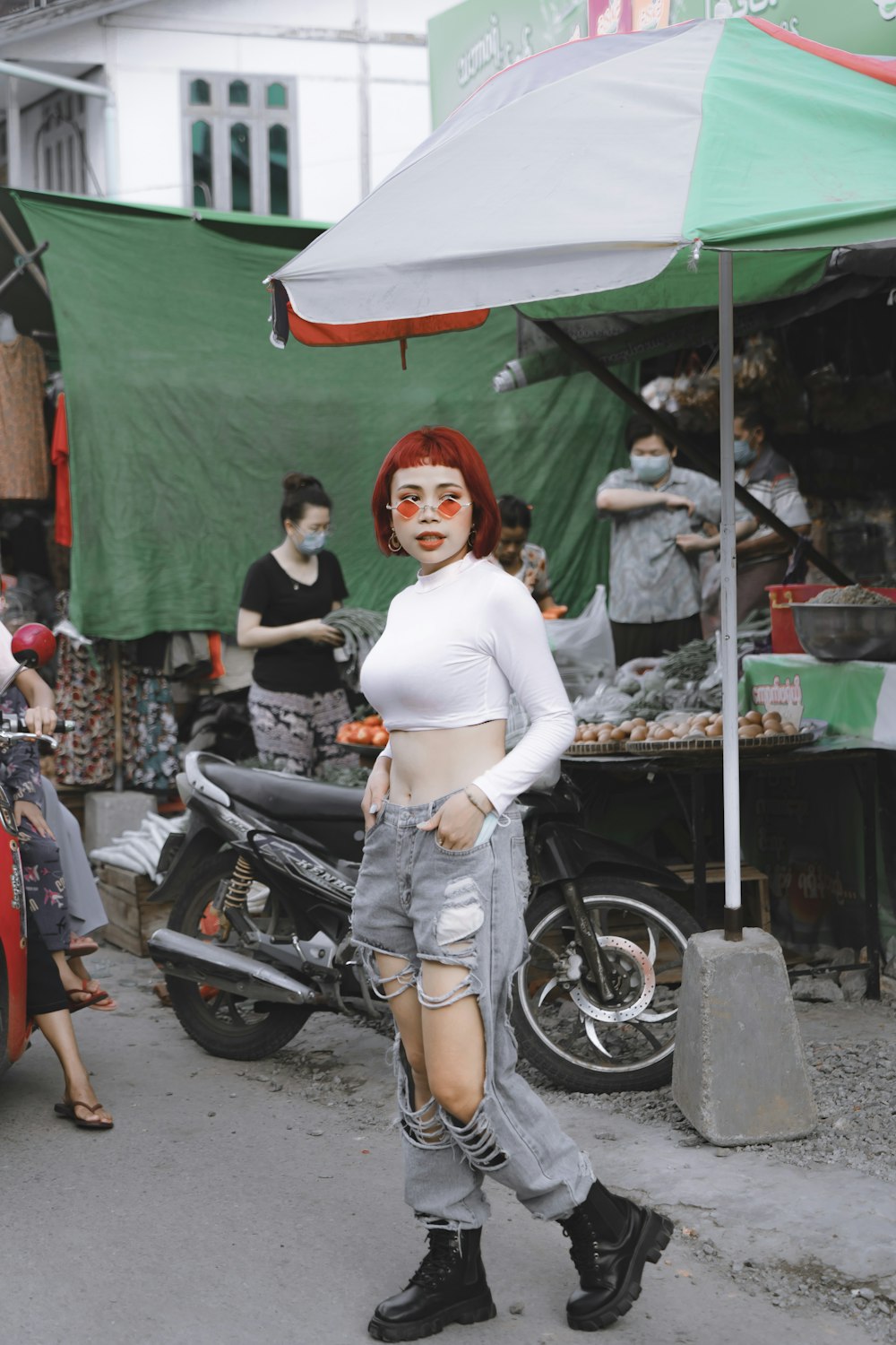 woman in white long sleeve shirt and blue denim daisy dukes standing on motorcycle during daytime