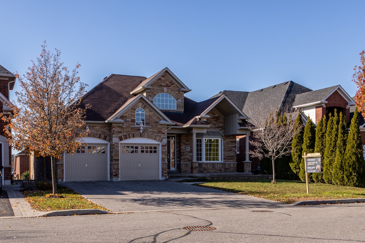 brown and white wooden house near green trees under blue sky during daytime