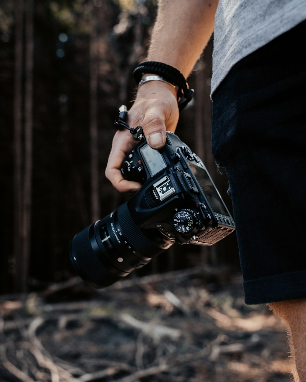 person in black pants holding black dslr camera