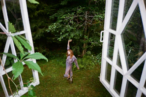 A dancer moving slowly with flowing aqua fabric in a garden setting