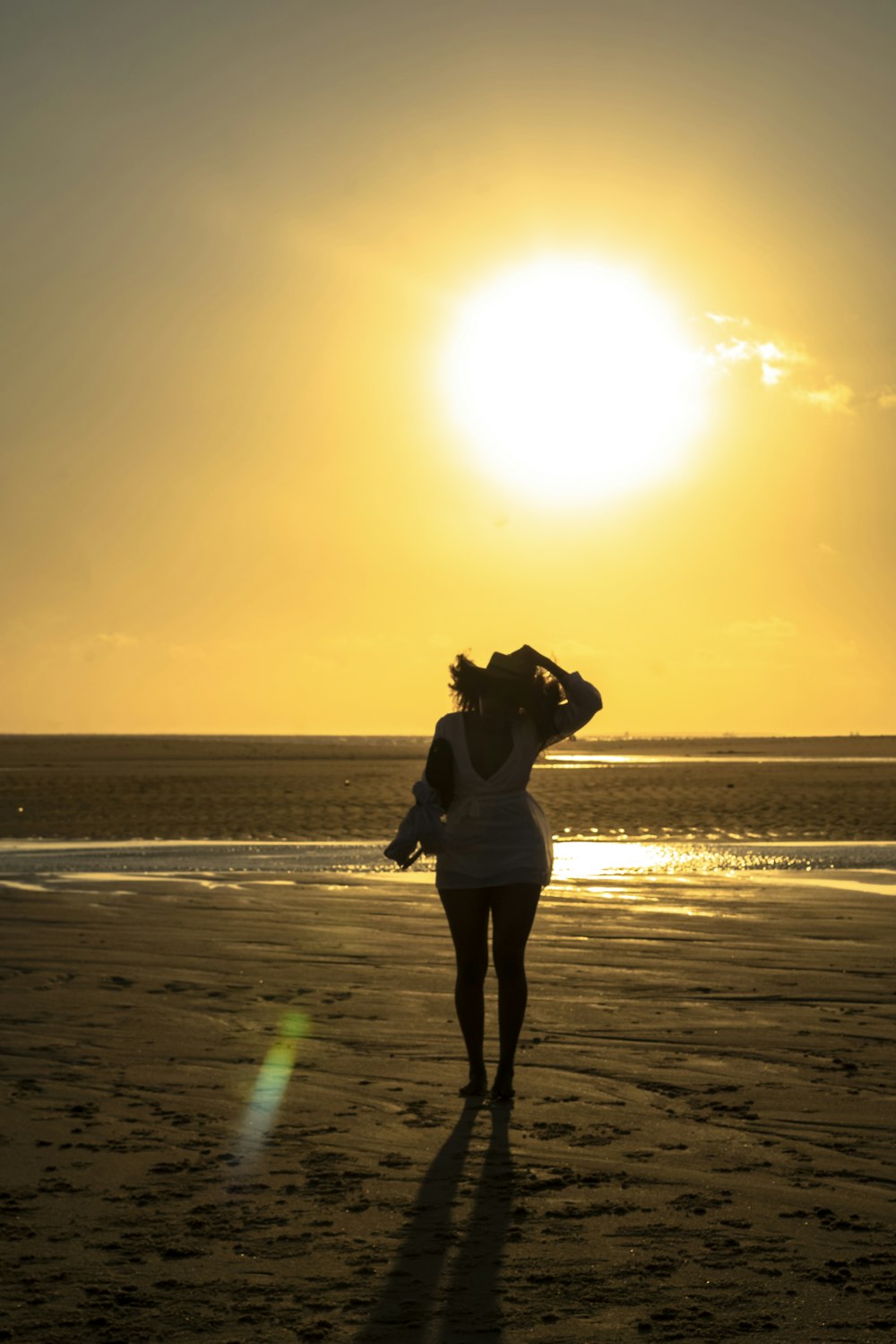 woman in black jacket and pants standing on beach during sunset