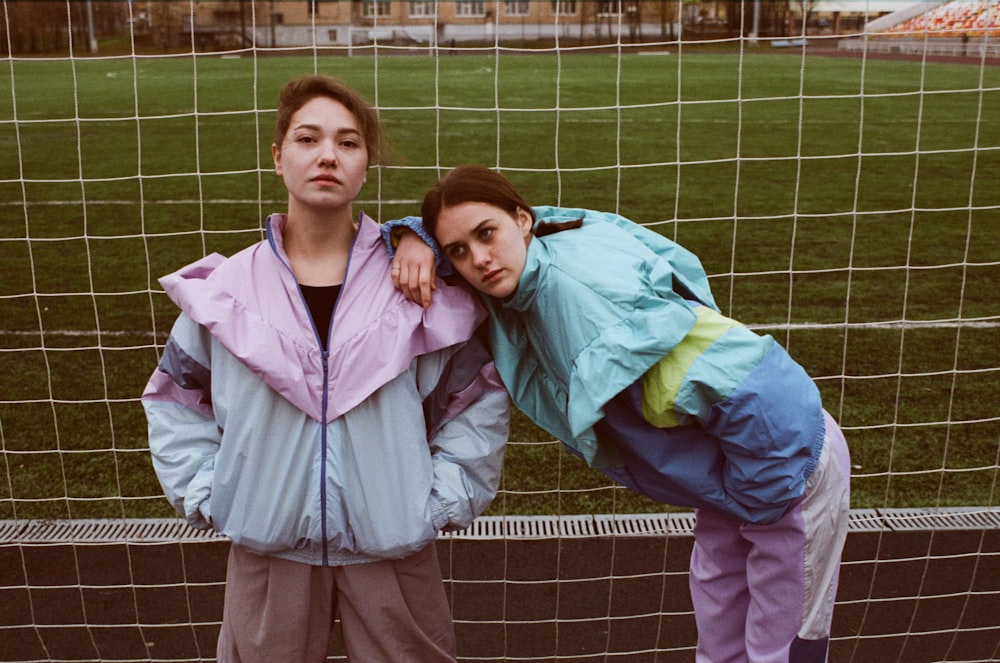 girl in pink zip up jacket standing beside girl in green jacket