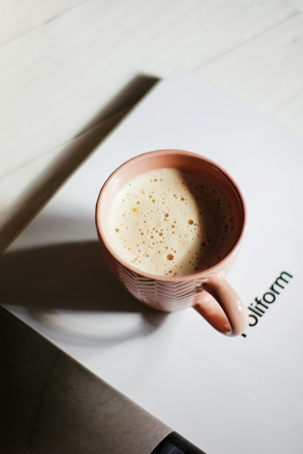 white and brown ceramic mug with brown liquid