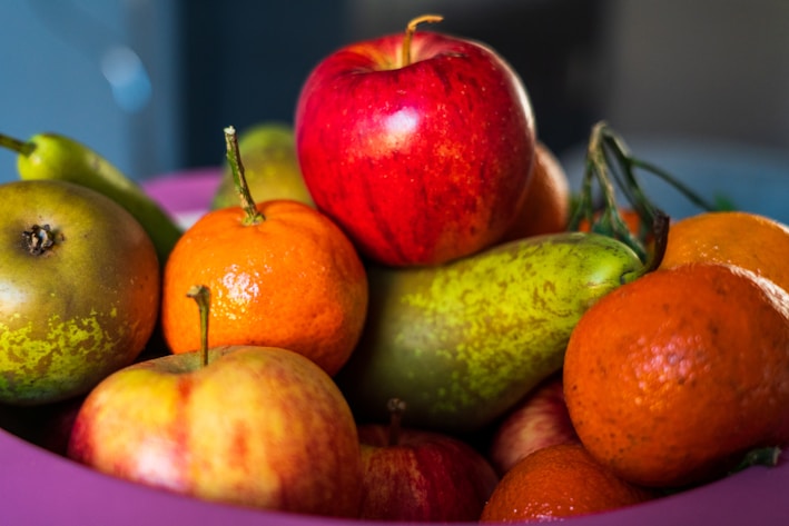 A colorful assortment of fresh fruits including apples, bananas, and oranges arranged in a rustic basket.