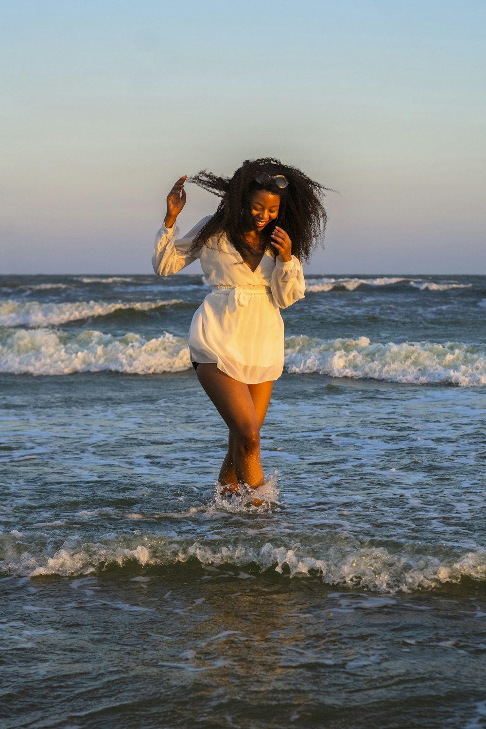 woman in white dress shirt standing on seashore during daytime