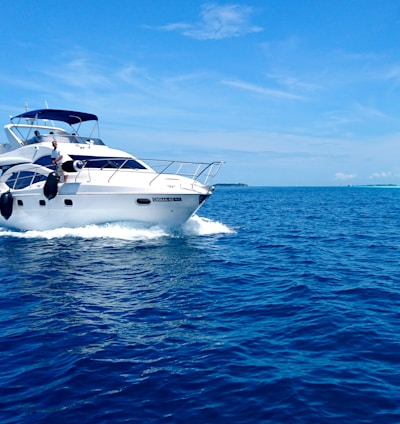 white and blue yacht on sea under blue sky during daytime