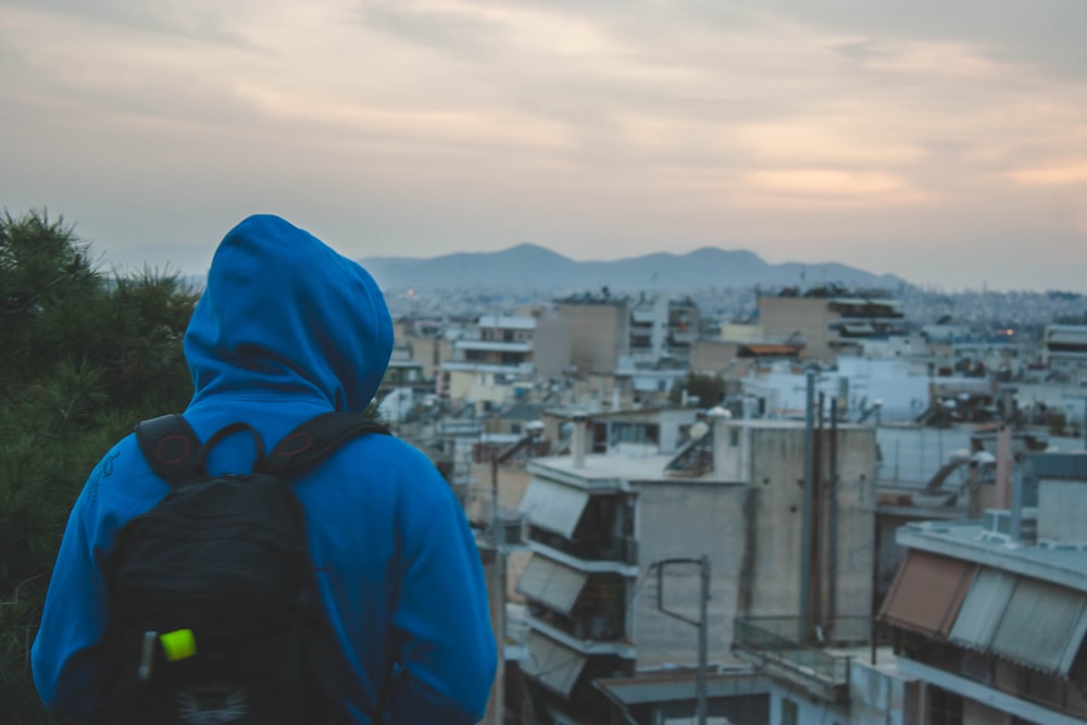 person in blue hoodie standing on top of building during daytime