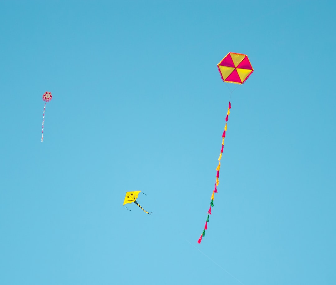 yellow and blue kite flying under blue sky during daytime