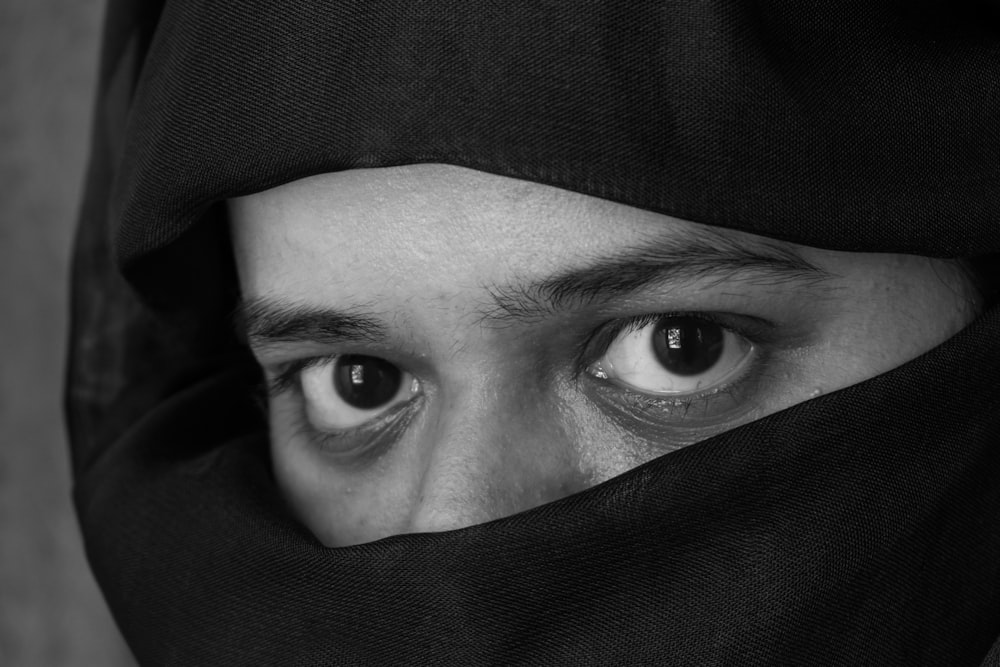Graustufenfoto einer Person, die das Gesicht mit Textil bedeckt
