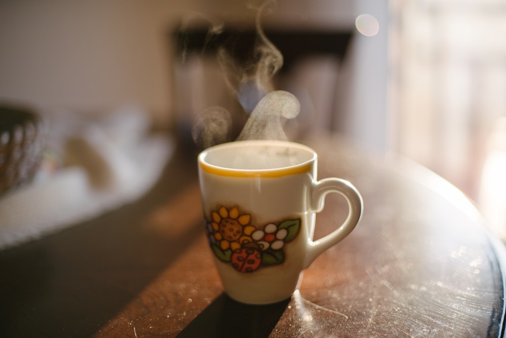 white and red floral ceramic mug on brown wooden table