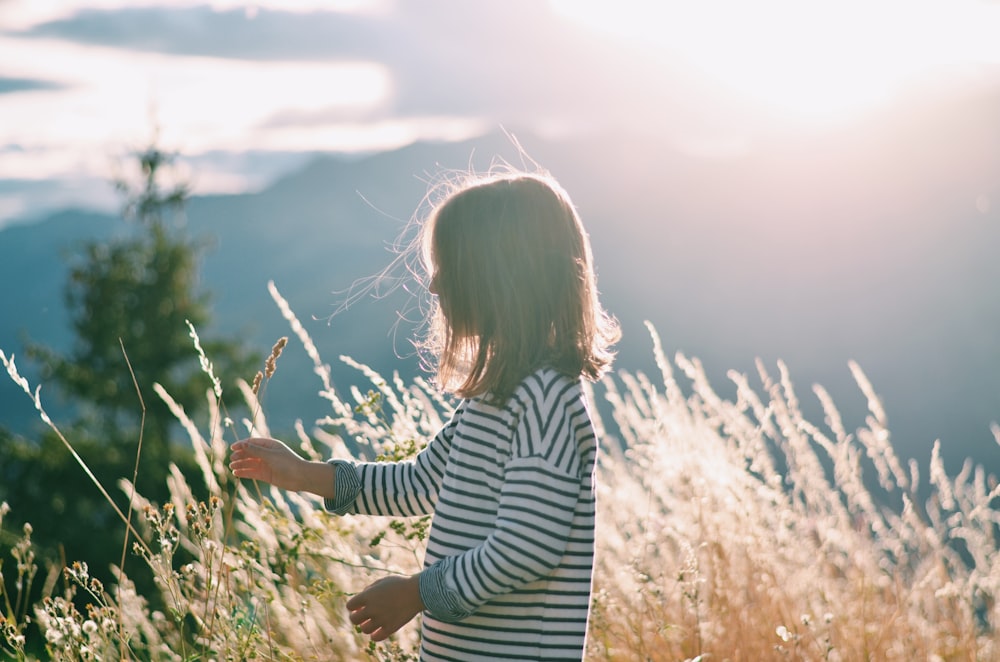 woman in black and white striped long sleeve shirt standing on brown grass field during daytime