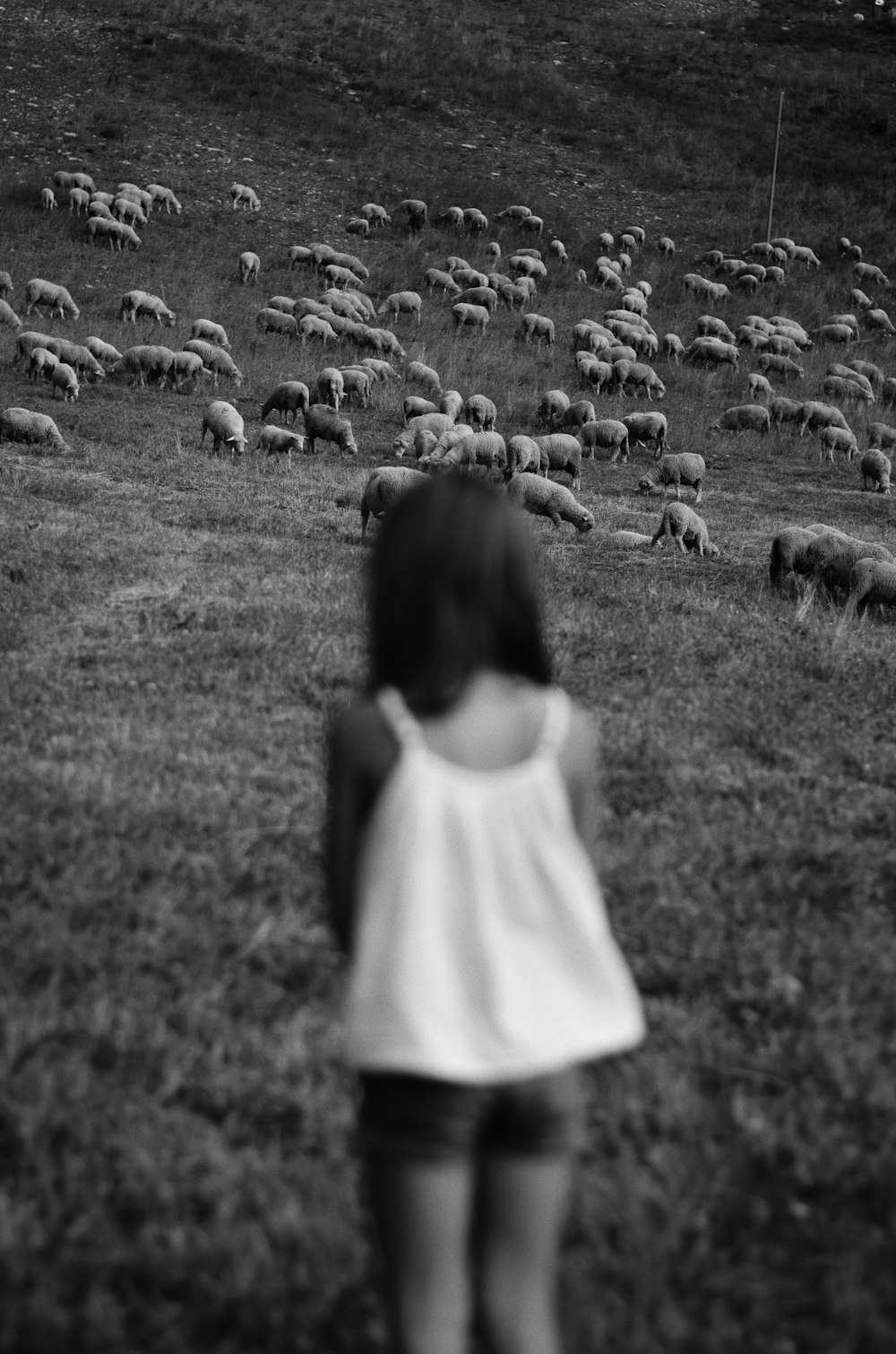 Muchacha en vestido blanco de pie en el campo de hierba