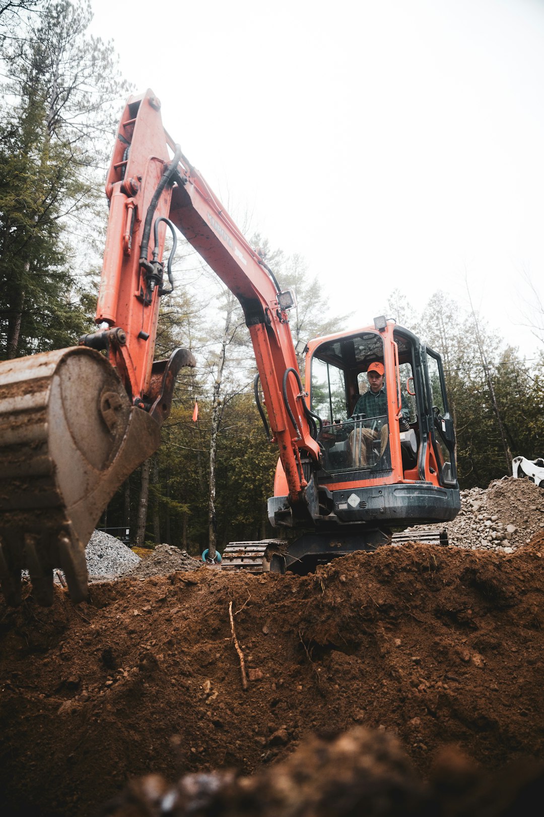 man in blue jacket and blue denim jeans riding orange excavator